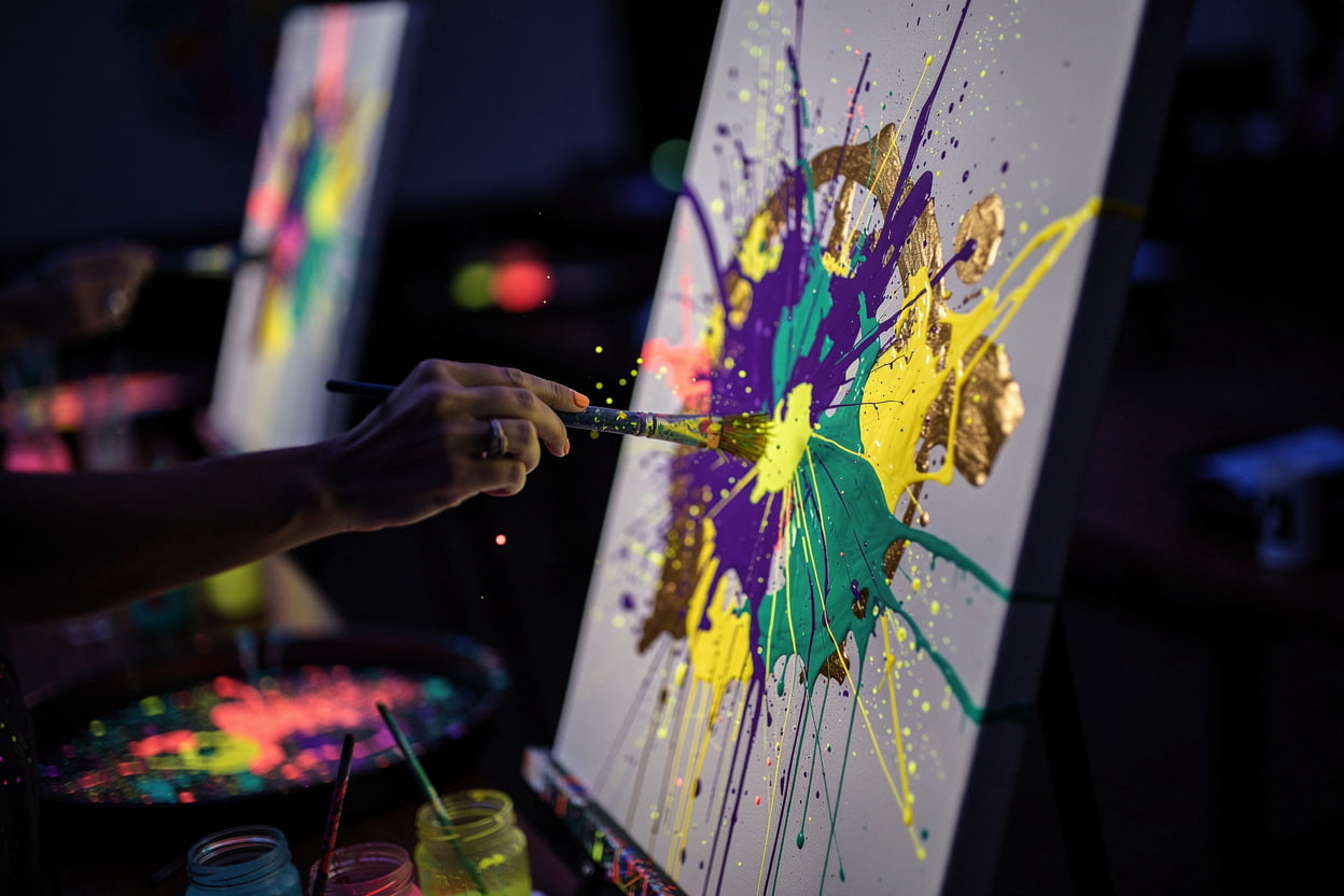 Splasherist Bath UV painting night with glowing neon splashes of paint on canvas in a dark studio atmosphere
